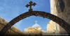 Church archway and dome under blue sky.