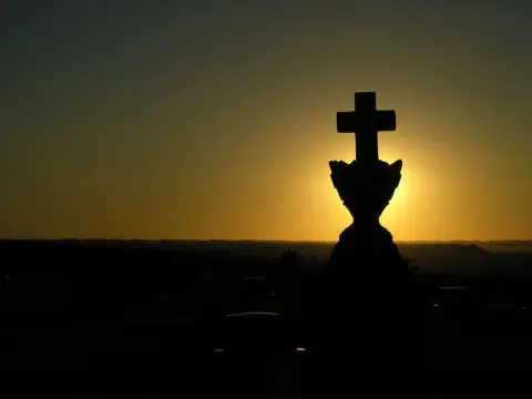 A cross sign in the middle of a sunset