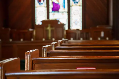 Church pews with stained glass background.
