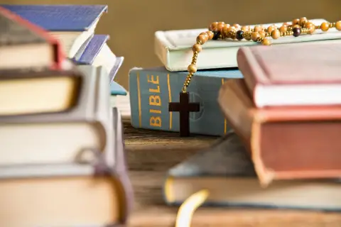 The Bible and other books with praying beads on a table