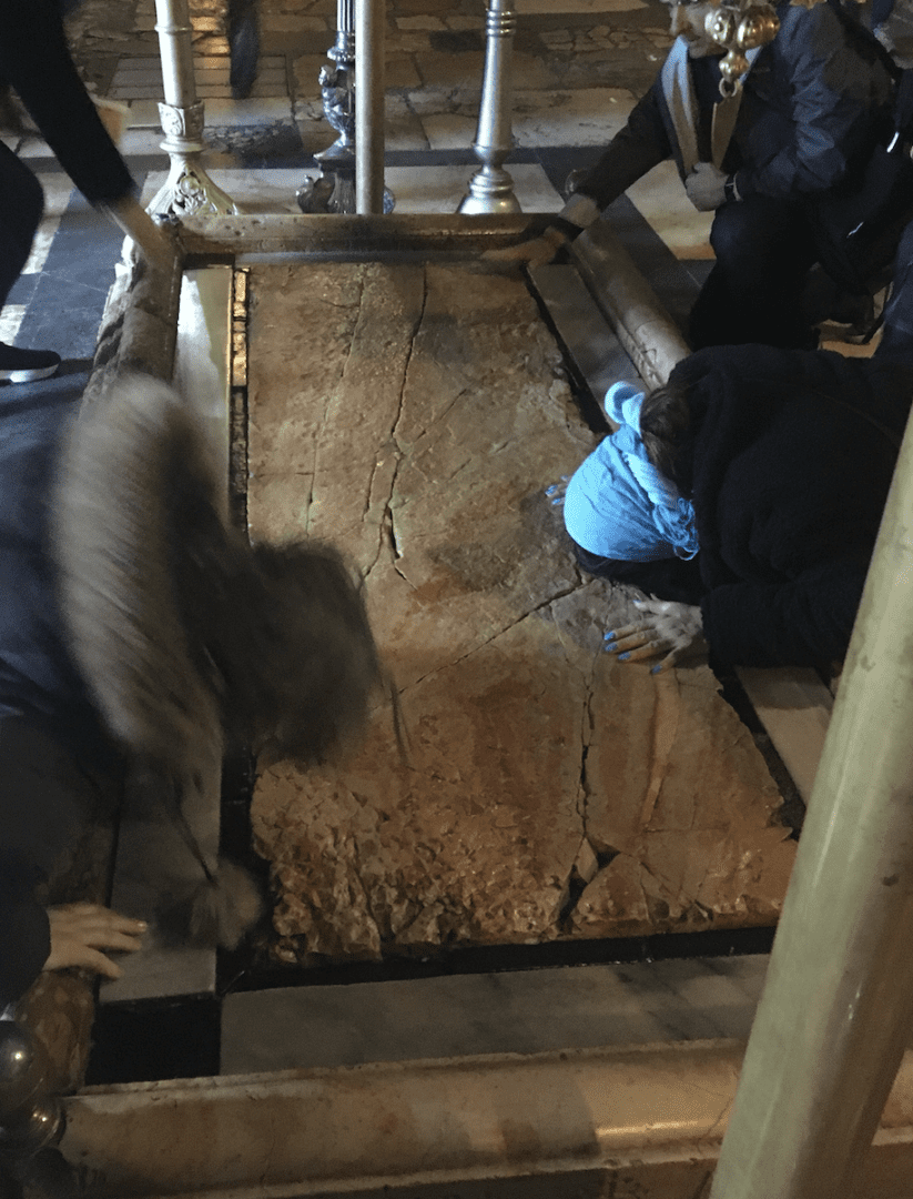 People praying at a sacred stone slab.