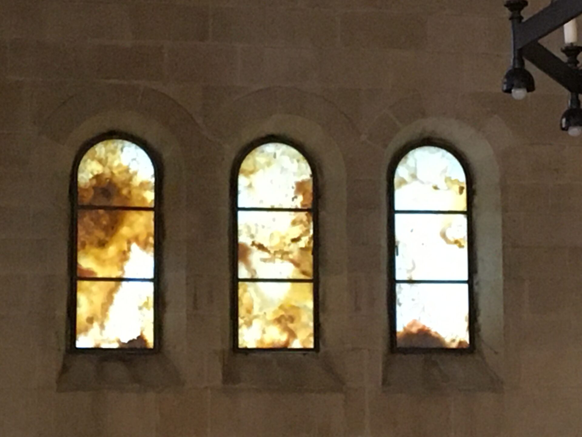 Three stained glass windows with abstract designs.