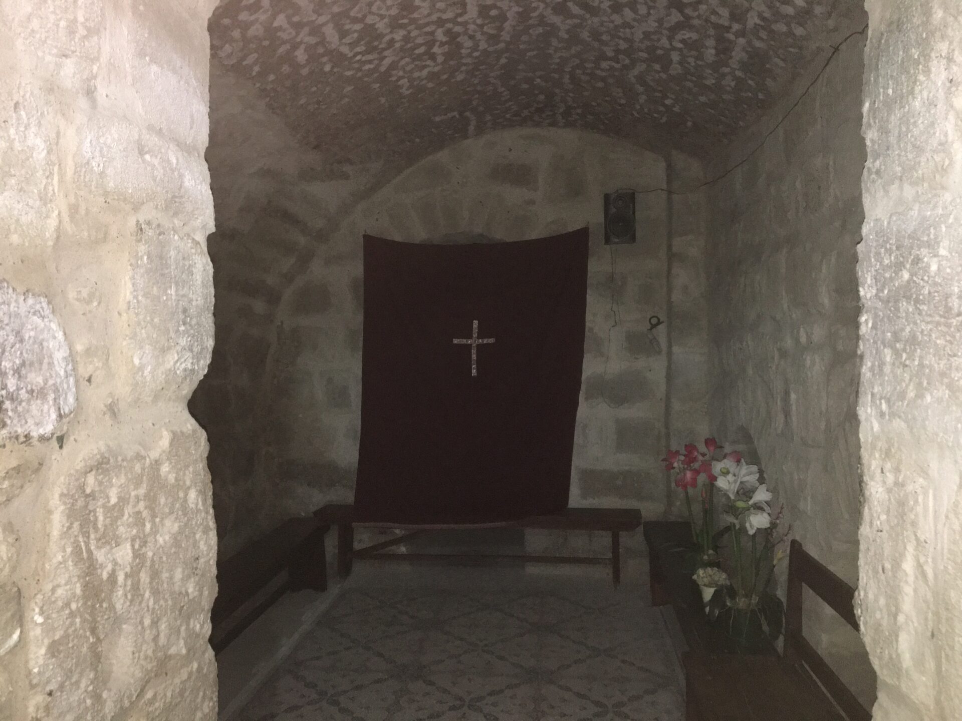 Stone room with cross and flowers.