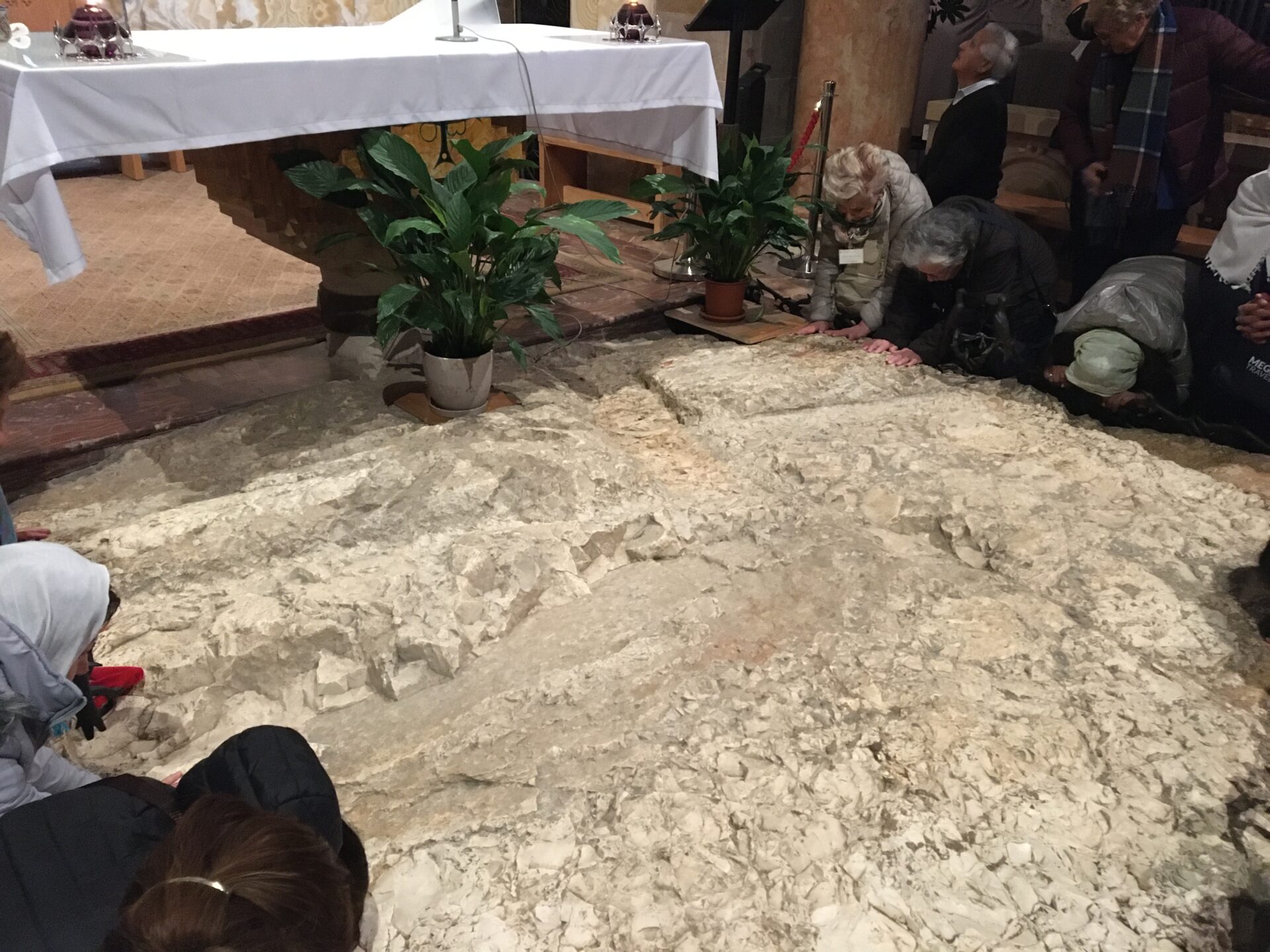 People praying on stone floor in church.