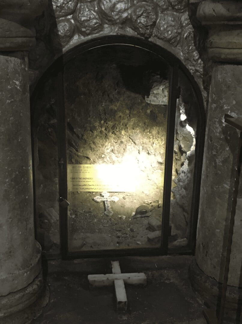 Glass-covered cave area with small cross inside.
