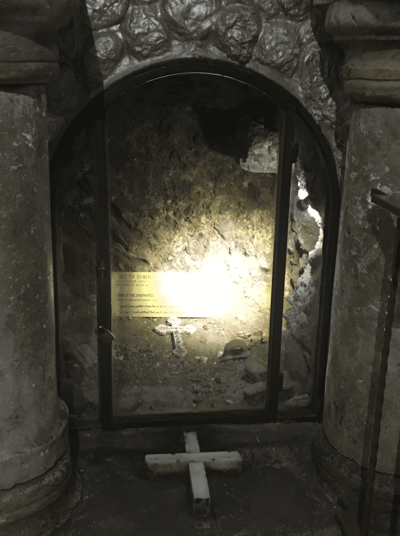 Glass-covered cave area with small cross inside.