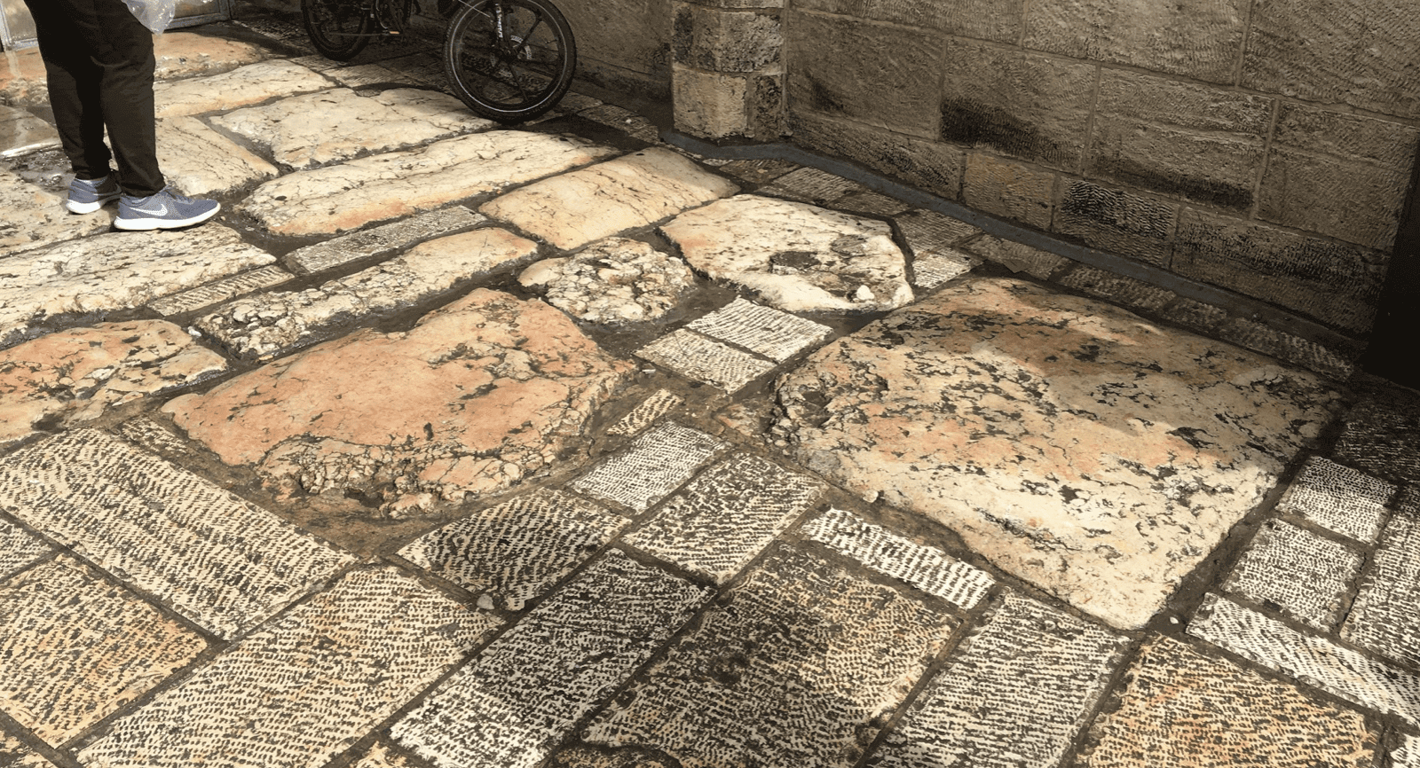 Stone pavement with bicycle and person nearby.
