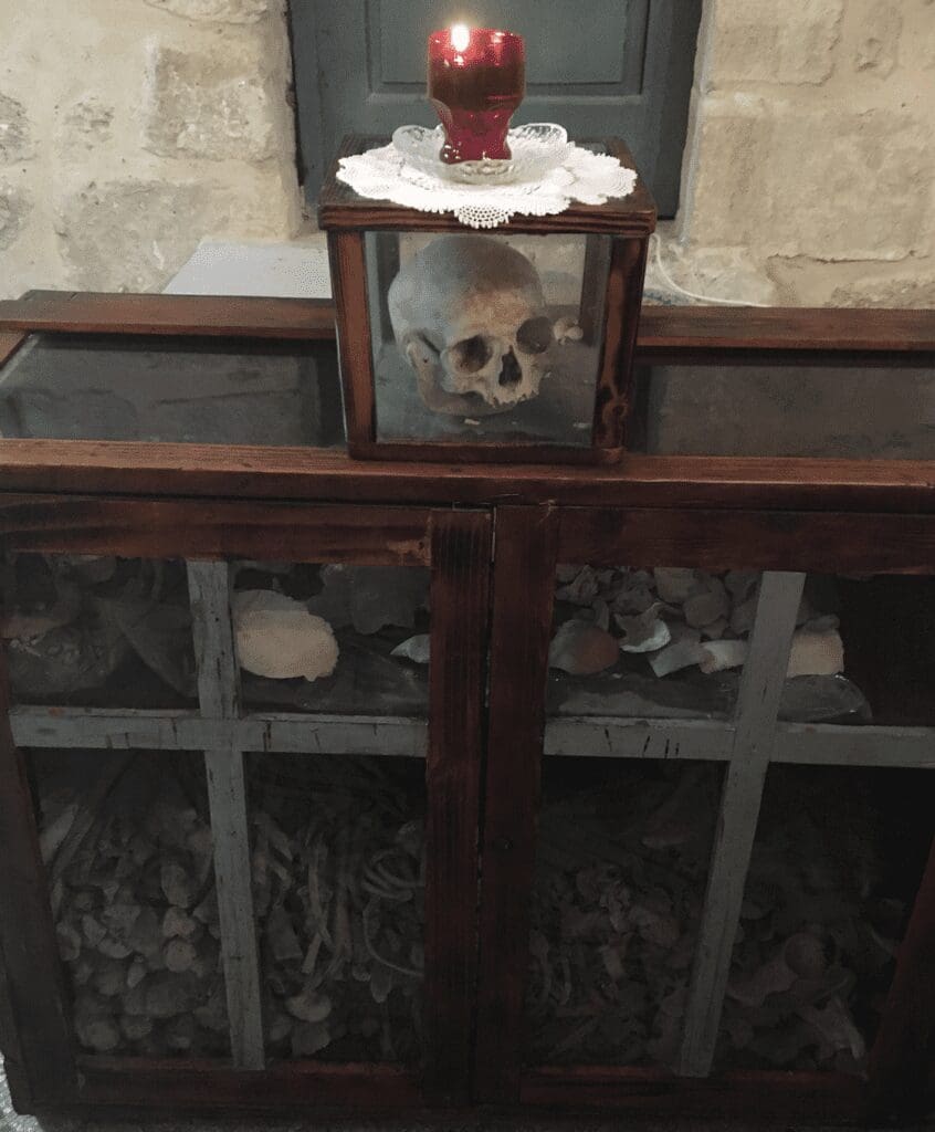 Skull in glass box with red candle.