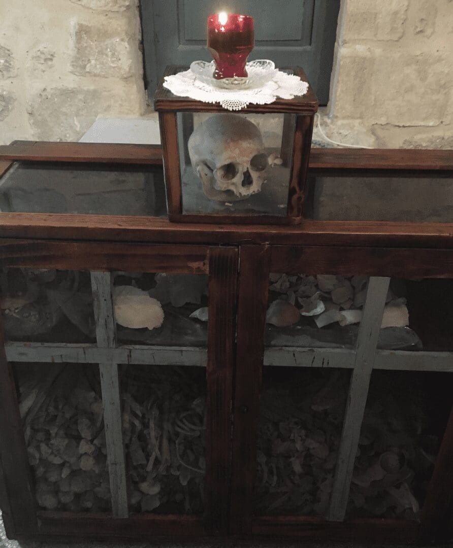 Skull in glass box with red candle.