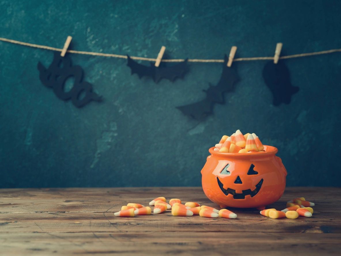 A pumpkin shaped bowl filled with candies