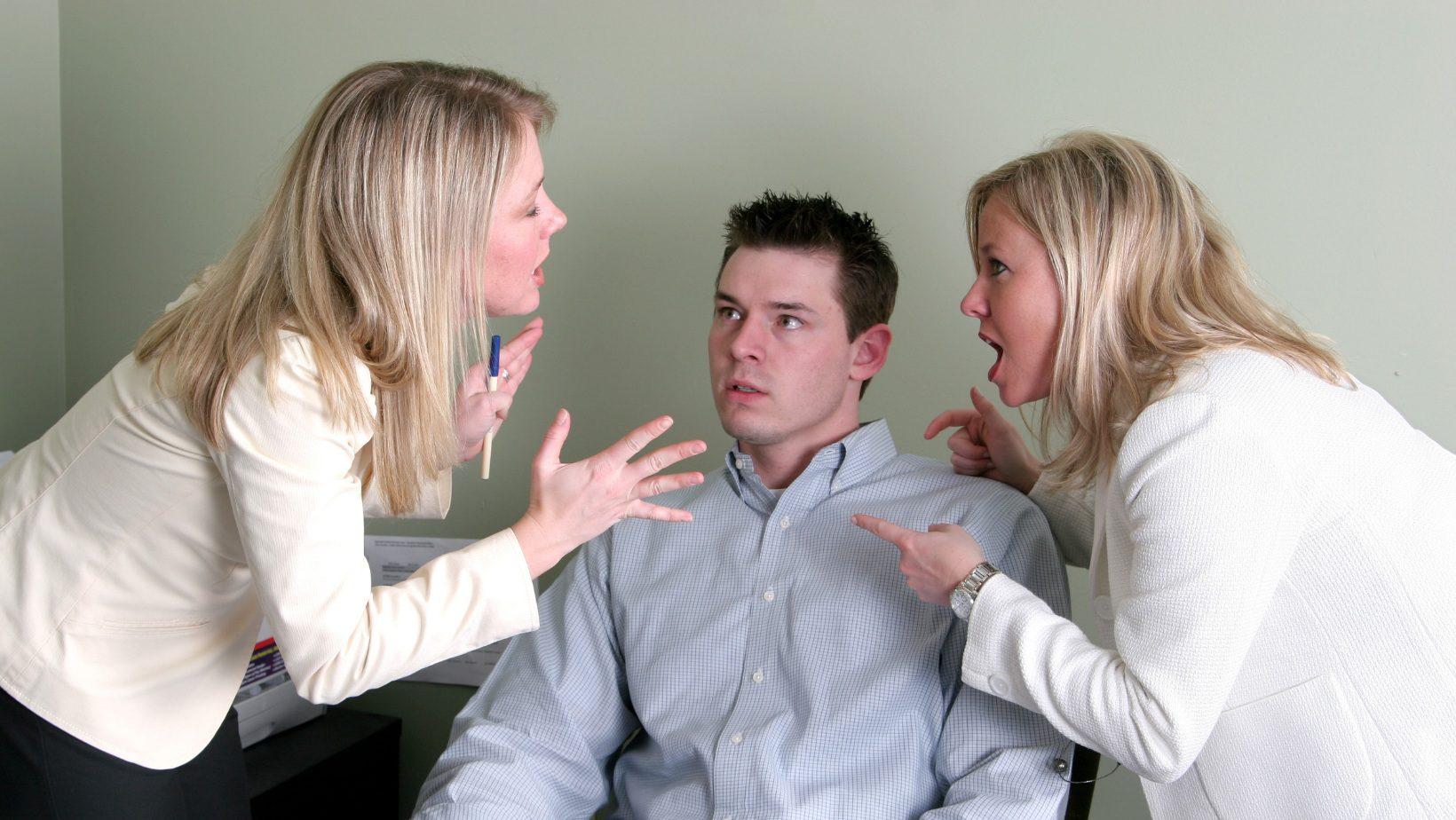 Two women shouting at a man inside a room