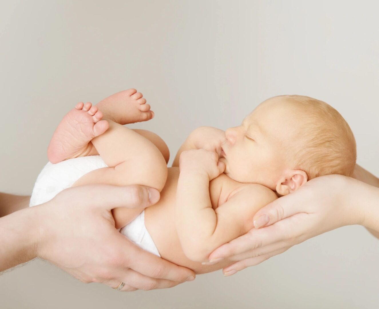 Two hands together holding a small baby