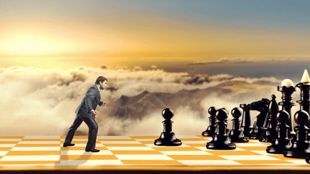Man facing giant chess pieces on board.