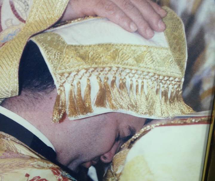 Priest receiving blessing during religious ceremony.