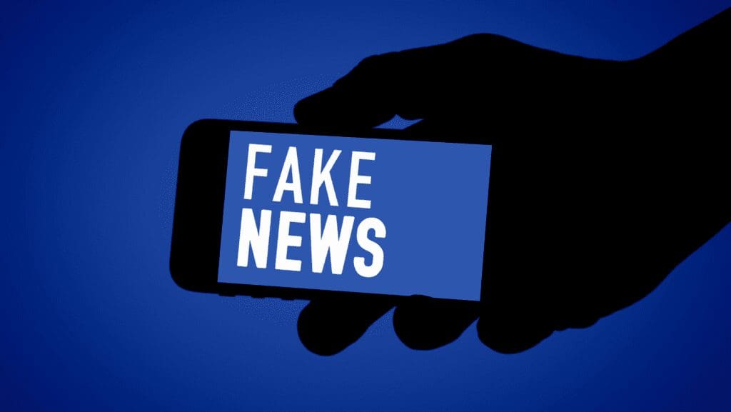 Hand holding phone displaying "Fake News".