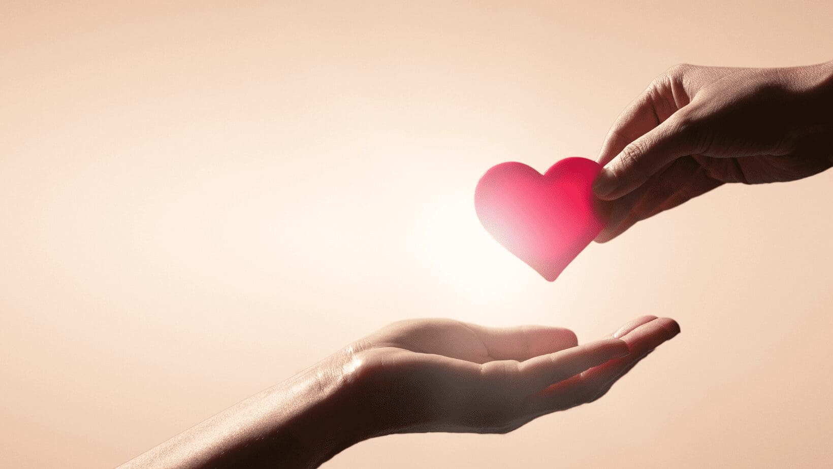 Hands exchanging a red heart symbol.