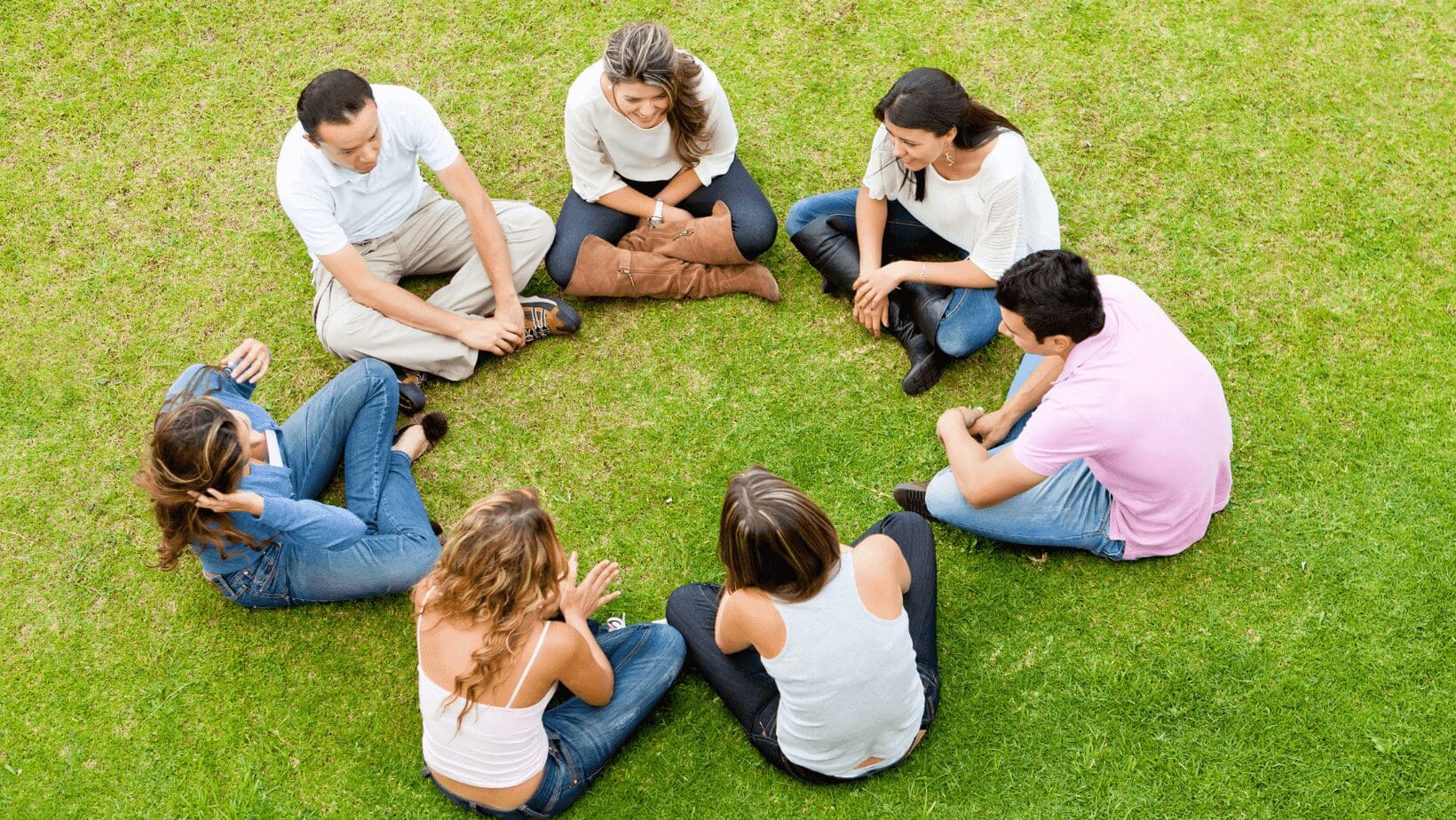 Group sitting in a circle on grass.