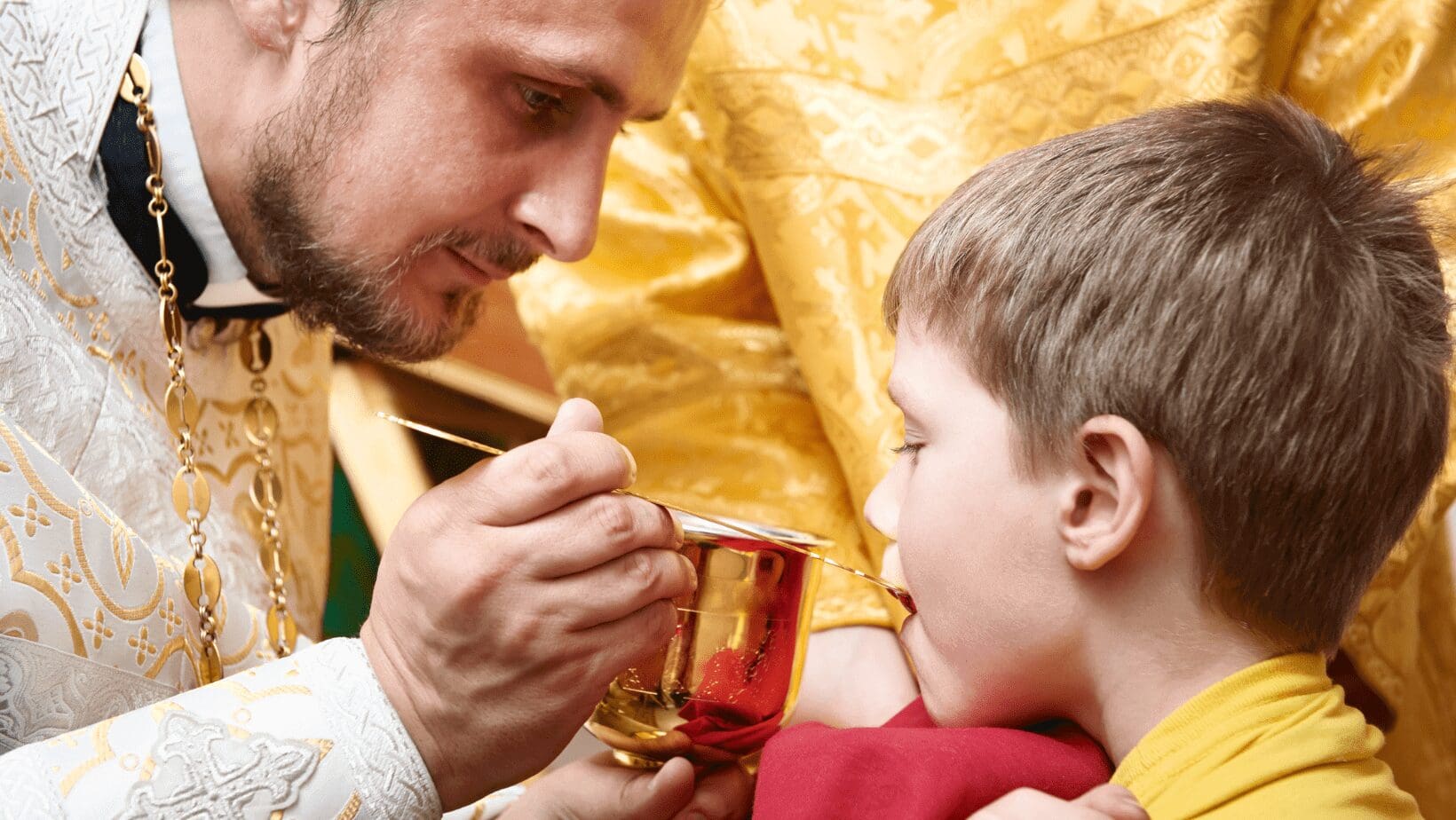 Priest giving communion to a child.