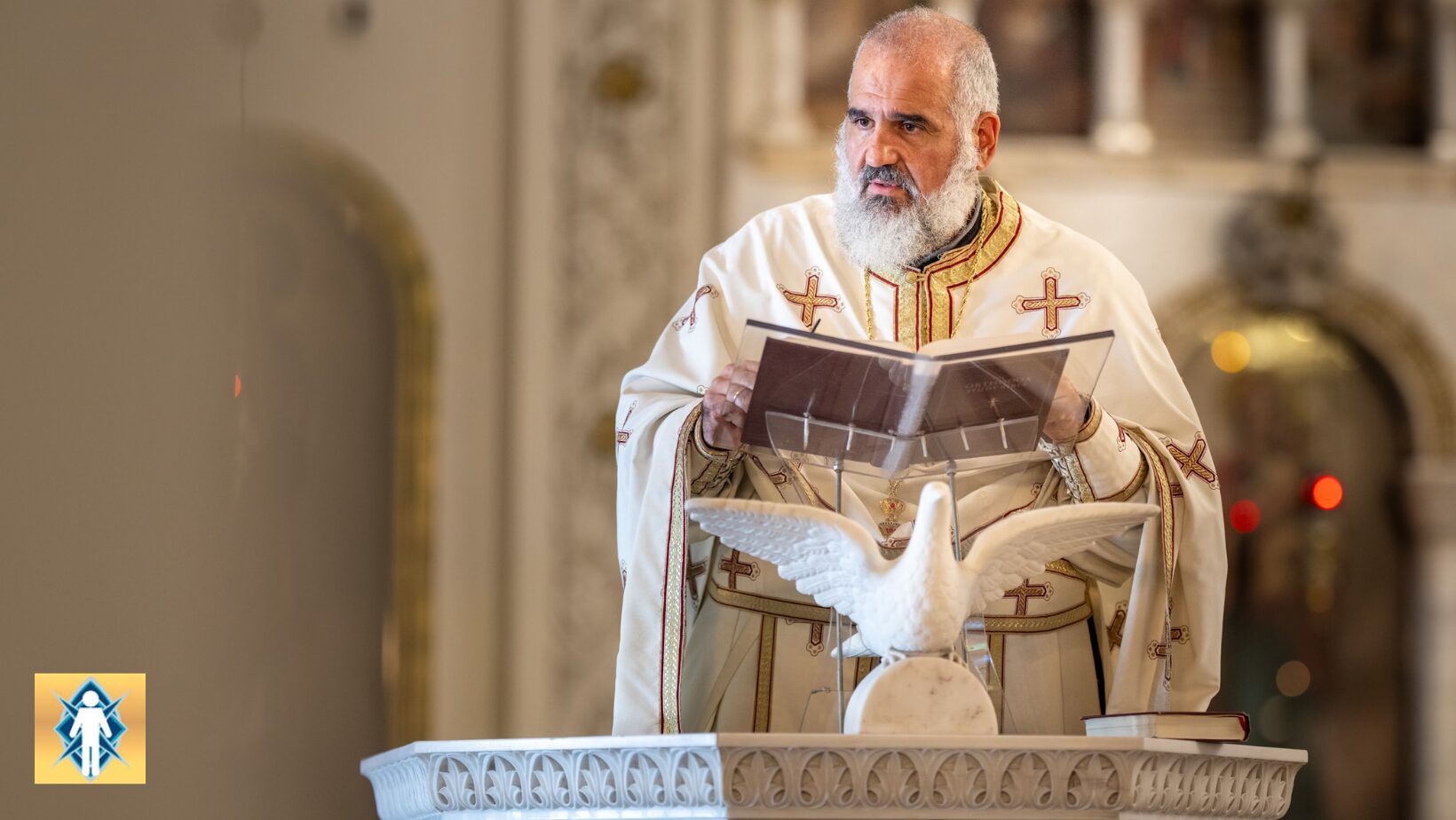 A priest holding a book with a dove flying near a baptismal font.