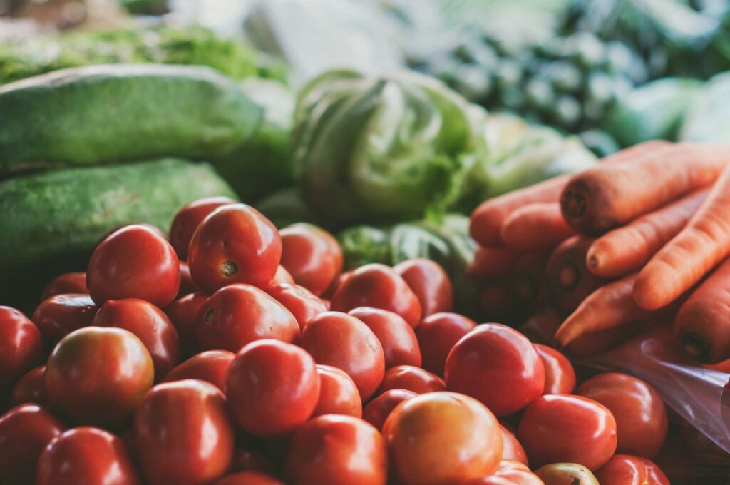 Close-up of fresh tomatoes with other vegetables in the background.