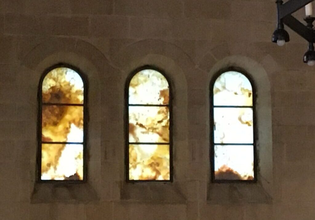 Three stained glass windows with abstract designs.