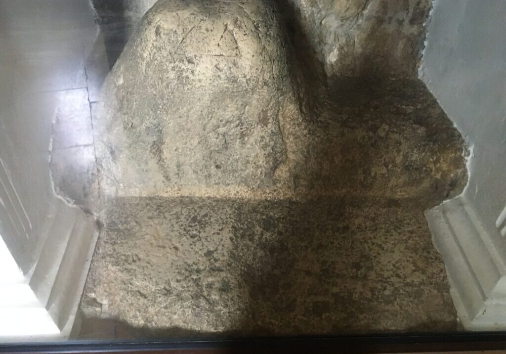 Rock formation displayed under protective glass case.