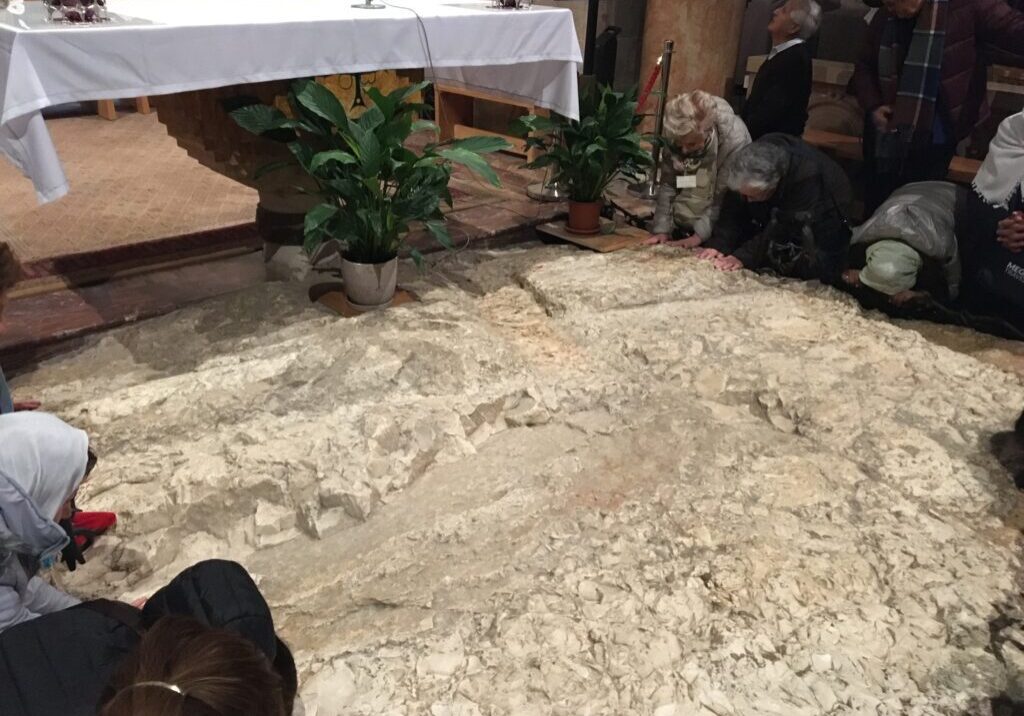 People praying on stone floor in church.