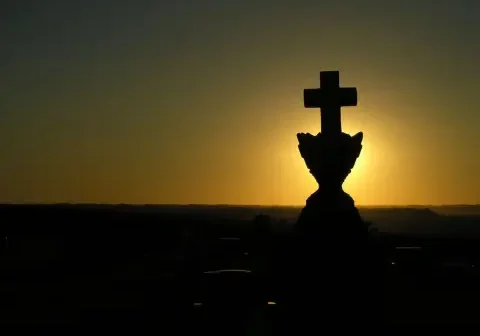 A cross sign in the middle of a sunset