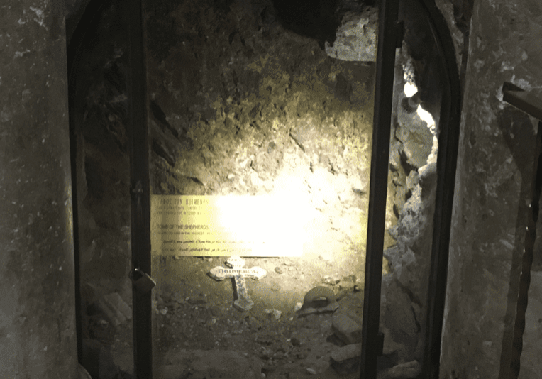 Glass-covered cave area with small cross inside.