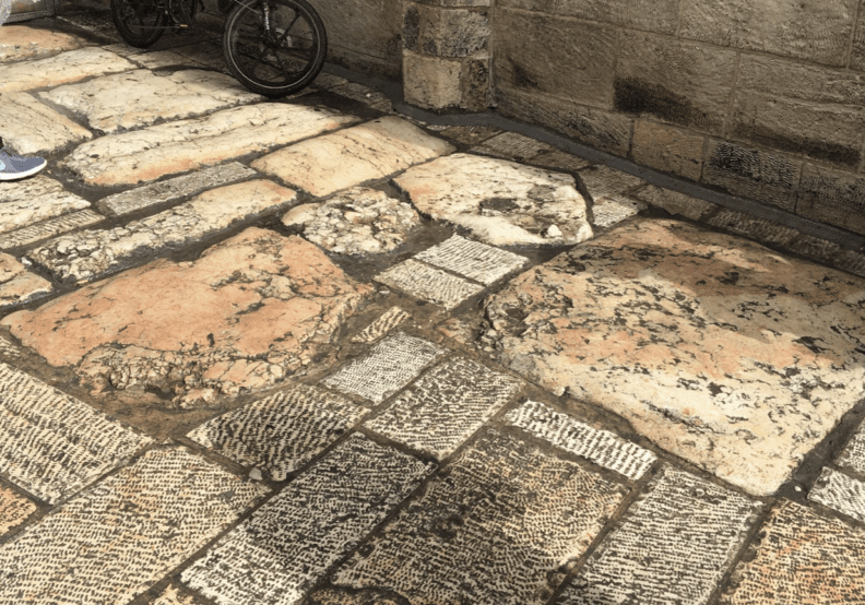 Stone pavement with bicycle and person nearby.