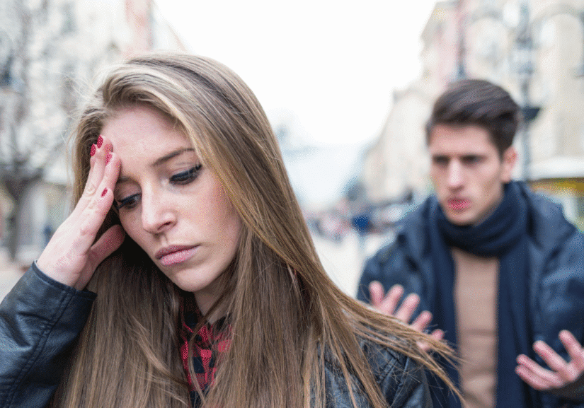Woman looking upset, man talking behind her.