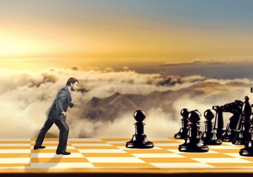 Man facing giant chess pieces on board.