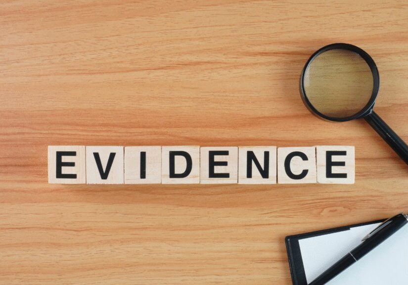 Scrabble tiles spell out the word 'EVIDENCE' with a magnifying glass and a note nearby.