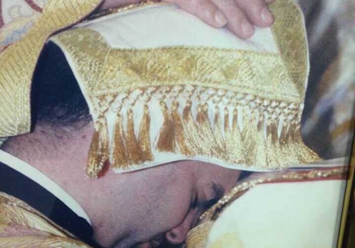 Priest receiving blessing during religious ceremony.