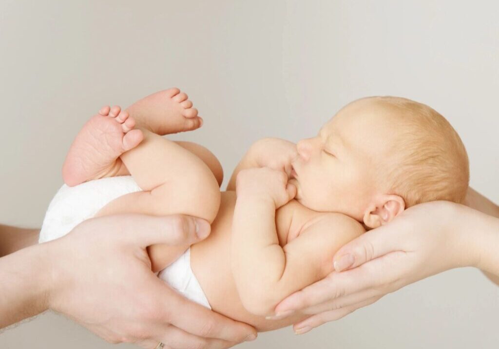 Two hands together holding a small baby