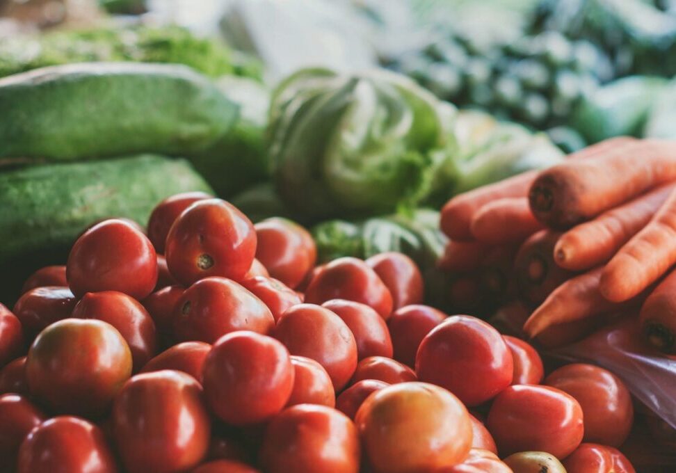 Close-up of fresh tomatoes with other vegetables in the background.