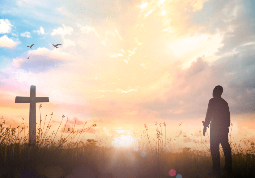 A man approaching a cross during sunrise