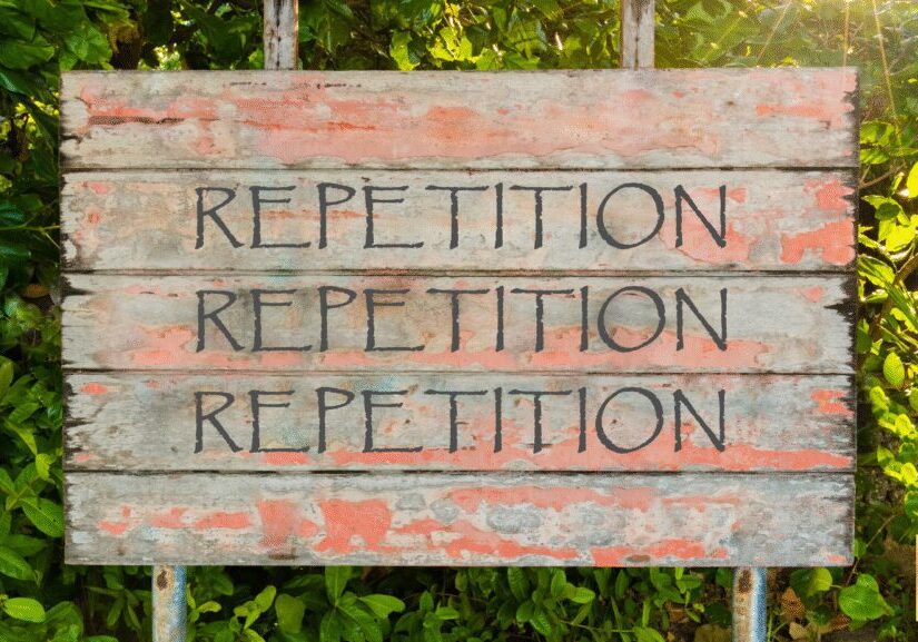 Wooden board with the word 'REPETITION' written multiple times.