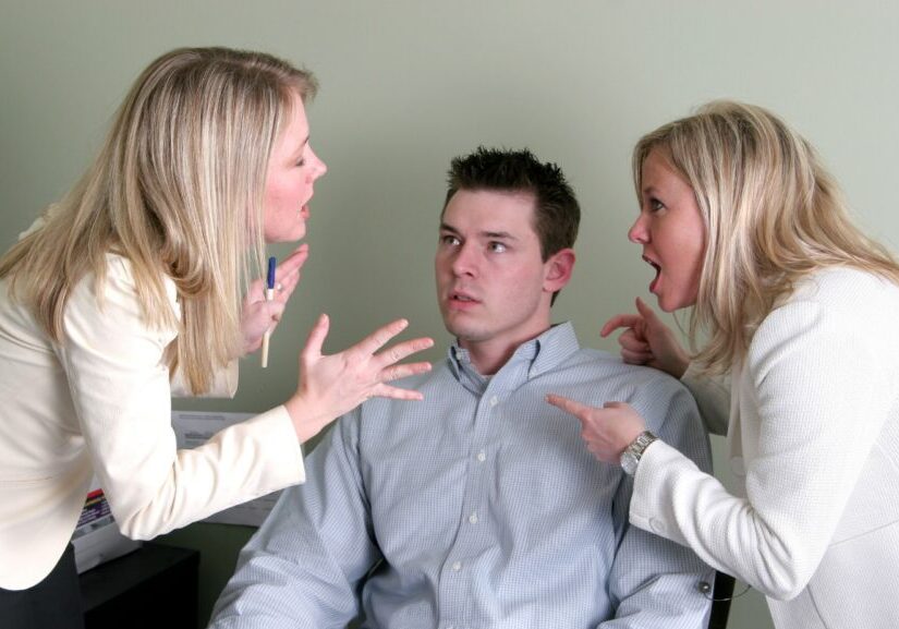 Two women shouting at a man inside a room